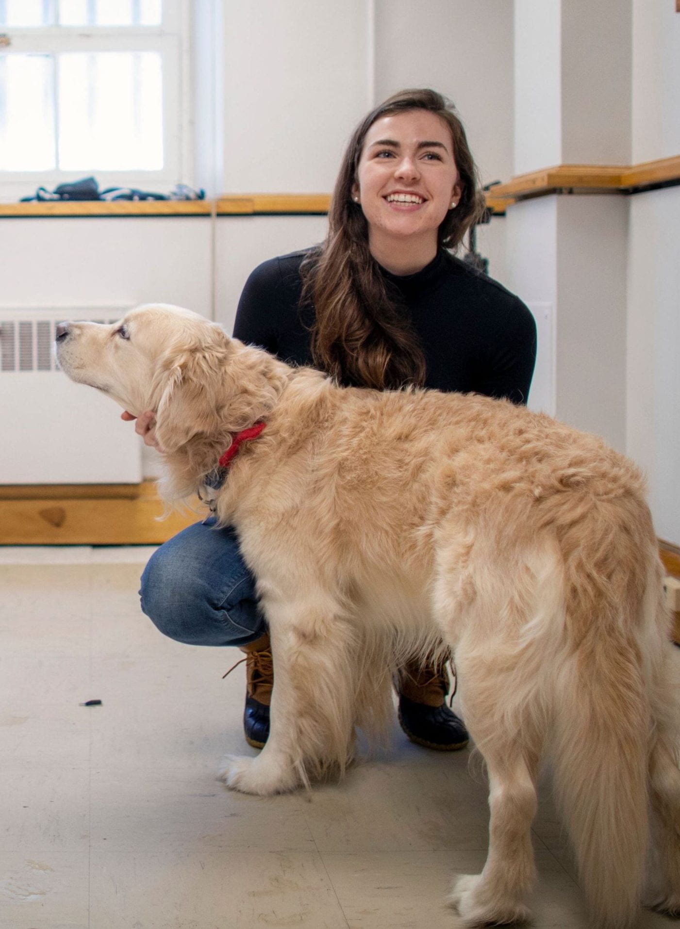 madeline pelgrim smiling and crouching down to pet a golden retriever