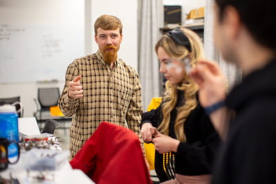 Eric Ewing, with beard and flannel shirt, working in his lab