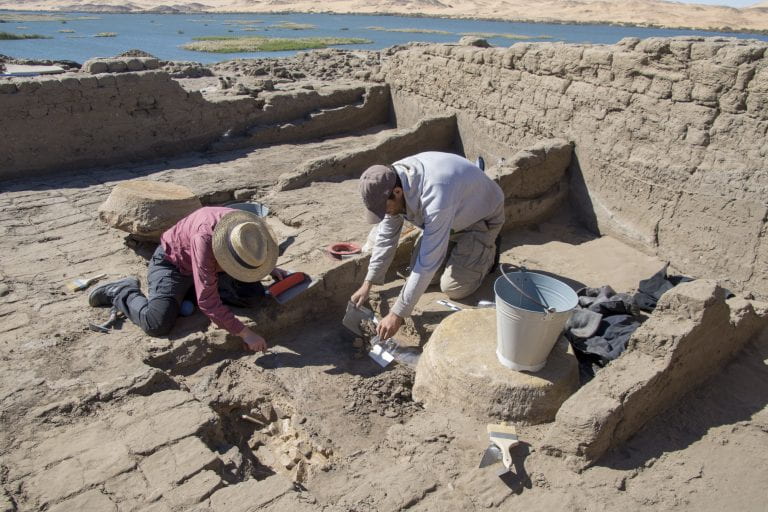 photo of archaeologists on their knees working