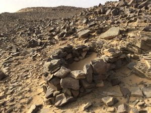 photograph of rocky desert with small circular structure of dry stones in foreground